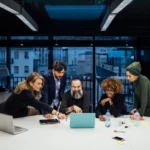 A group of five people collaborating on a project and discussing something on the laptop screen.